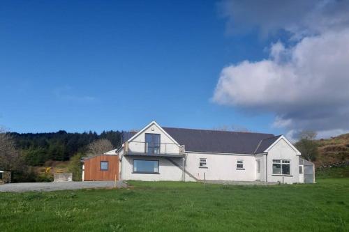 a large white house in a field of grass at The Hideaway Tragumna a hidden gem in the hills in Drishanebeg