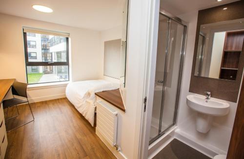 a bathroom with a sink and a shower and a bed at Willow Court in Stirling