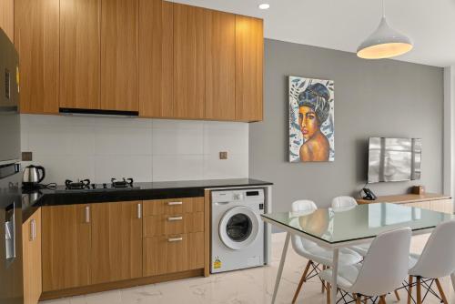 a kitchen with a washing machine and a glass table at MLZ Apartments Sihanoukville in Sihanoukville