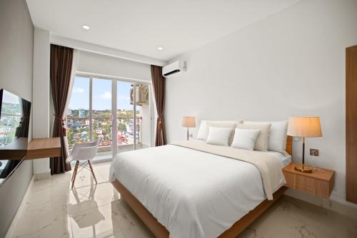 een slaapkamer met een groot wit bed en een raam bij MLZ Apartments Sihanoukville in Sihanoukville