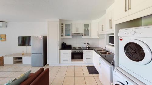 a kitchen with white cabinets and a washer at San Lameer Villa 2502 by Top Destinations Rentals in Southbroom