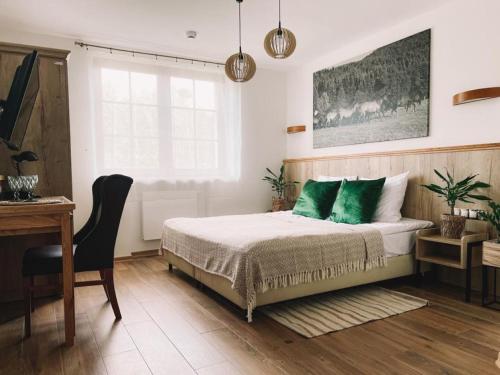 a bedroom with a bed with green pillows and a desk at Końska Dolina in Tylicz