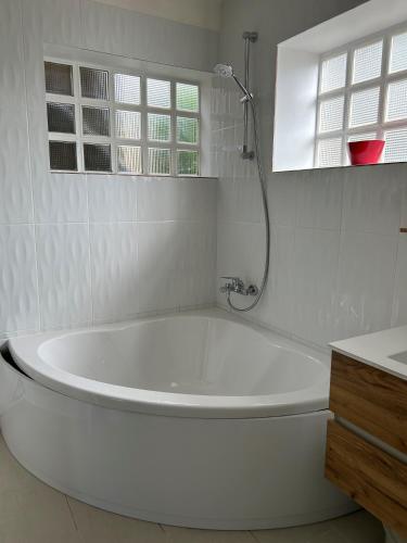 La salle de bains blanche est pourvue d'une baignoire et d'une fenêtre. dans l'établissement GITE INDEPENDANT en duplex proche mer COTE DE GRANIT ROSE, à Pleubian