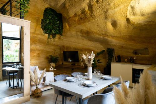 a dining room with a table and chairs and a tv at Le temps suspendu, Suite troglodyte & SPA privé in Doué-la-Fontaine