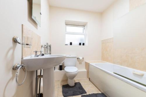 a bathroom with a sink and a toilet and a tub at Axinite - 3 Bedroom Flat With Parking in Southampton