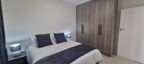 una camera da letto con un grande letto con cuscini blu di The Aura a Roodepoort