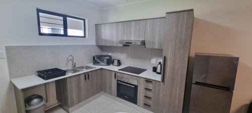 a small kitchen with a sink and a refrigerator at The Aura in Roodepoort