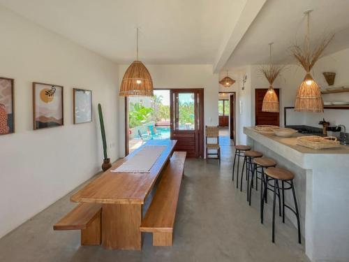 een keuken met een lange houten tafel en krukken bij Casa Vannina uma casa encantadora em Icaraizinho ! in Icaraí