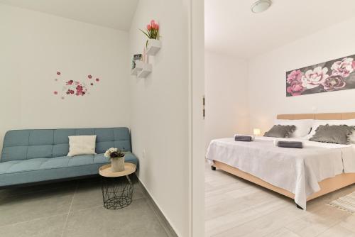 Cette chambre blanche dispose d'un lit et d'un canapé bleu. dans l'établissement Apartmani Castrum, à Kaštela