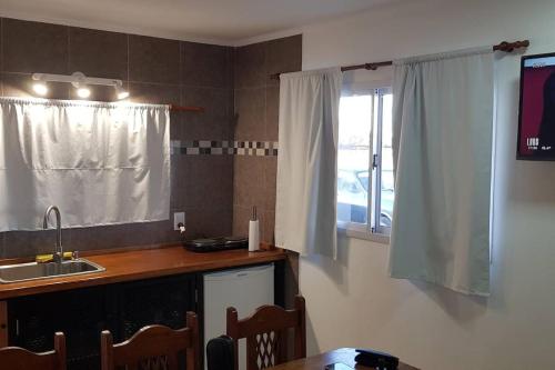 uma cozinha com um lavatório e um balcão com uma janela em Hermoso alojamiento temporario LA SOÑADA em Pigüé