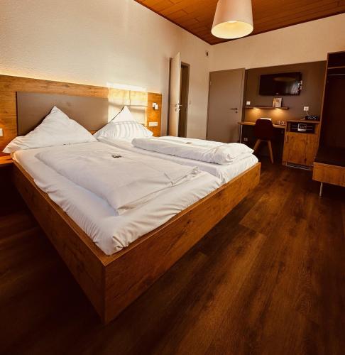 a bedroom with a large bed with white sheets at Hotel und Wirtshaus Löwen in Rielasingen-Worblingen