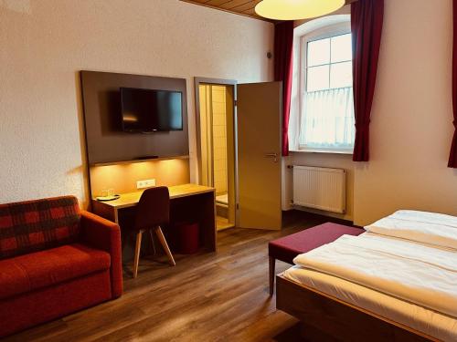 a hotel room with a bed and a chair and a desk at Hotel und Wirtshaus Löwen in Rielasingen-Worblingen