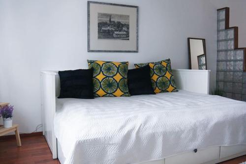 Cozy studio in Tampere for 2 with own Sauna,balcony and a free parking في تامبير: غرفة نوم بسرير ابيض مع مخدات صفراء وسوداء