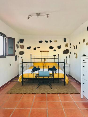 1 dormitorio con 1 cama y pared de piedra en Coqueto apartamento en El Cuchillo, en Tinajo