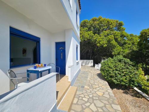 a white house with a blue door and a patio at Pavlis Studios Ormos in Marathokampos