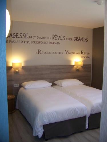two beds in a hotel room with a sign on the wall at ibis Styles Vierzon in Vierzon