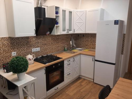 een keuken met witte kasten en een witte koelkast bij Апартаменти з власним двориком in Khotov