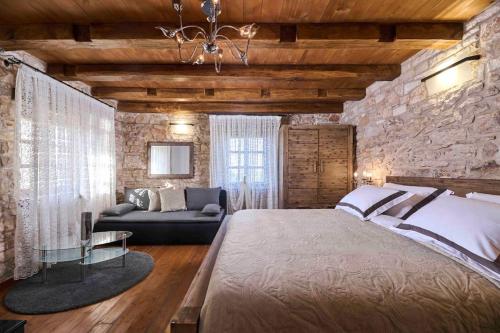 a bedroom with a large bed and a stone wall at San Niccolo in Vilanija