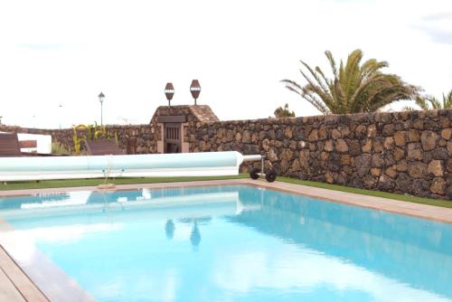 a swimming pool in front of a stone wall at Casa Serendipia in La Asomada