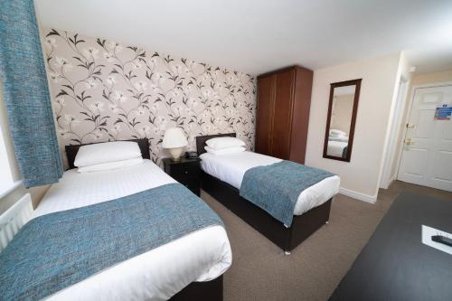 a hotel room with two beds and a wall at The Angel Hotel in Leamington Spa