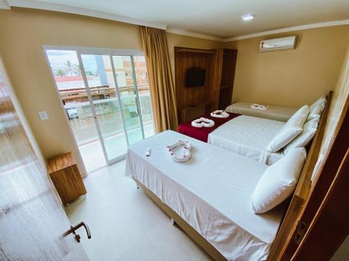 a hotel room with two beds and a balcony at FLAT BADEJO in Japaratinga