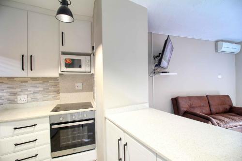 a kitchen with white cabinets and a brown leather chair at San Lameer Villa 2004 by Top Destinations Rentals in Southbroom