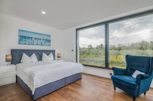 a bedroom with a bed and a blue chair and a window at Luxury Villa Weiss - Malinska - heated Pool in Malinska