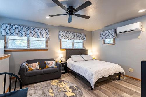 a bedroom with a bed and a couch and a ceiling fan at Sea Cave, OBX gem, private studio, couple's nest! in Kill Devil Hills