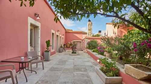 un patio de una casa rosa con mesa y sillas en Arhontiko Arhanes Suites en Archanes