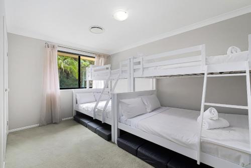 two bunk beds in a room with a window at Heated Pool, Beach Side Entetainer, Sleeps 18 in Umina