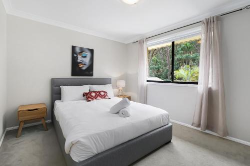 a bedroom with a large bed and a window at Heated Pool, Beach Side Entetainer, Sleeps 18 in Umina