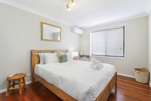 a bedroom with a large white bed and a window at Heated Pool, Beach Side Entetainer, Sleeps 18 in Umina