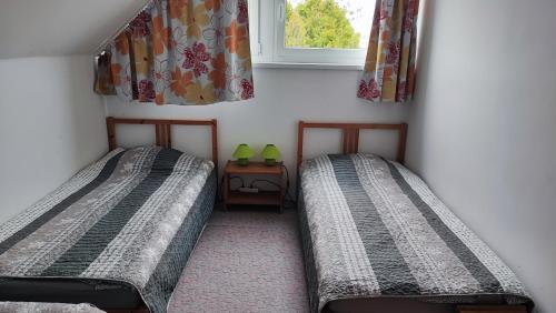 two twin beds in a room with a window at Siófoki nyaralóház in Siófok
