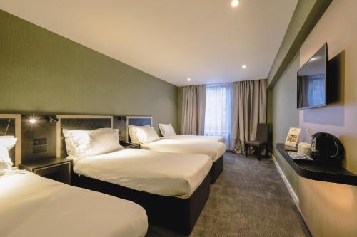 Habitación de hotel con 3 camas y TV de pantalla plana. en Royal National Hotel, en Londres