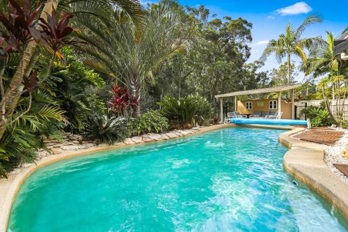 a pool in a backyard with palm trees and a house at Heated Pool, Beach Side Entetainer, Sleeps 18 in Umina