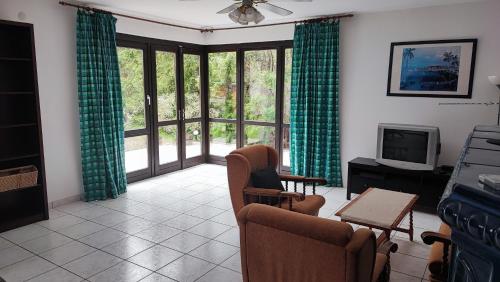 a living room with green curtains and a tv at Siófoki nyaralóház in Siófok