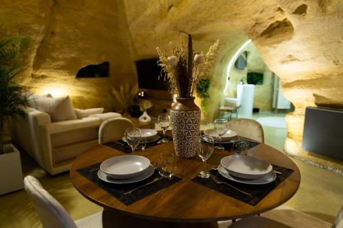 un comedor con una mesa con platos y copas de vino en La falaise perdue : Suite troglodyte grandiose en Doué-la-Fontaine