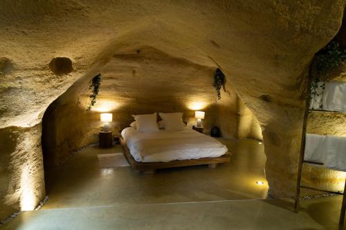 una camera da letto in una grotta con un letto di La falaise perdue : Suite troglodyte grandiose a Doué-la-Fontaine