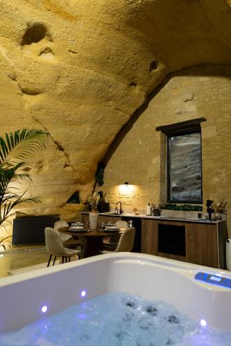une pièce avec une baignoire et une table et une cuisine dans l'établissement La falaise perdue : Suite troglodyte grandiose, à Doué-la-Fontaine