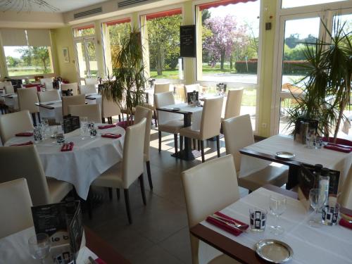 un restaurant avec des tables blanches, des chaises et des fenêtres dans l'établissement Logis De La Loire, à Ancenis