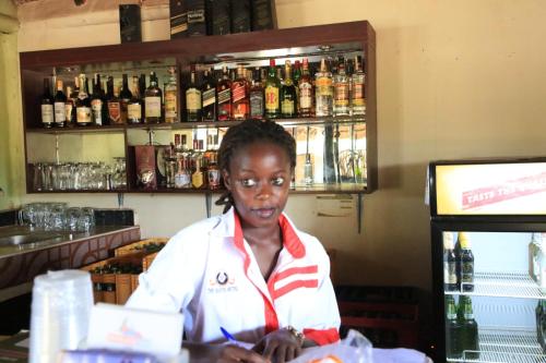 una mujer sentada en un mostrador en un bar en The Roots classic hotel, en Njeru