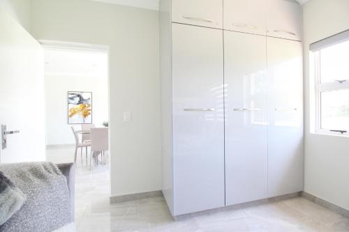 a white kitchen with white cabinets and a table at Caribbean 1136 by Top Destinations Rentals in Port Edward