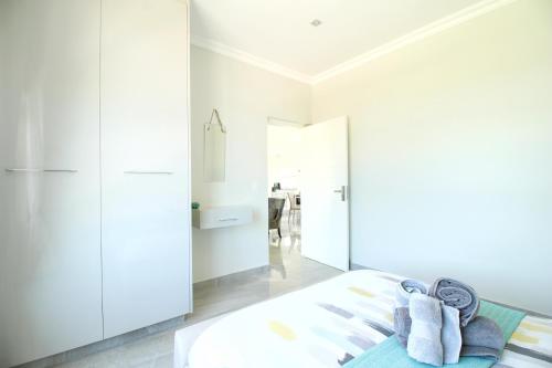 a bedroom with white walls and a bed with towels at Caribbean 1136 by Top Destinations Rentals in Port Edward
