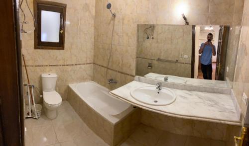 بهجة بالاس 3 للشقق السكنية في الغردقة: رجل يلتقط صورة للحمام مع مغسلة وحوض استحمام