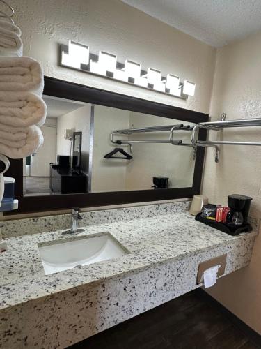 a bathroom with a sink and a large mirror at Ambassador Inn in Perryton