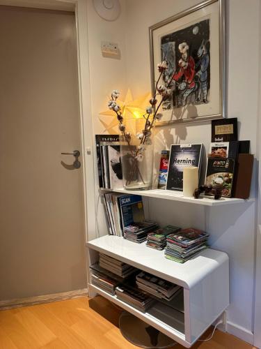 a white book shelf with books and a vase of flowers at Helts B&B - Helts Guesthouse in Herning