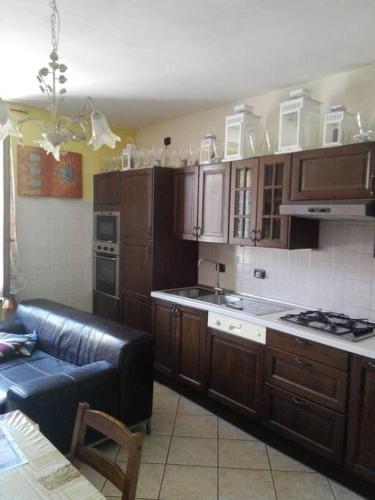 une cuisine avec des placards en bois et un canapé en cuir noir dans l'établissement Appartamento in cascina lombarda, à Caselle Lurani