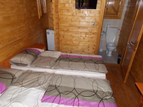 a group of four beds in a room with a toilet at Căsuțe Suzanne Băile Figa in Beclean