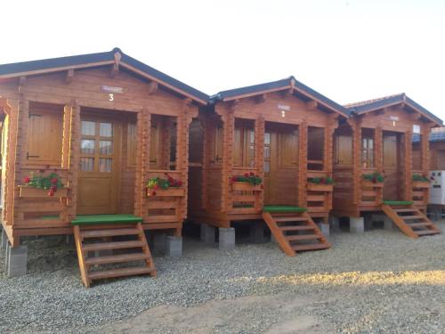 a row of wooden cabins with benches in front at Căsuțe Suzanne Băile Figa-cu aer conditionat in Beclean