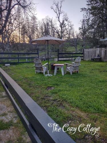 a picnic table and two chairs with an umbrella at Cozy Cottage in Miramonte